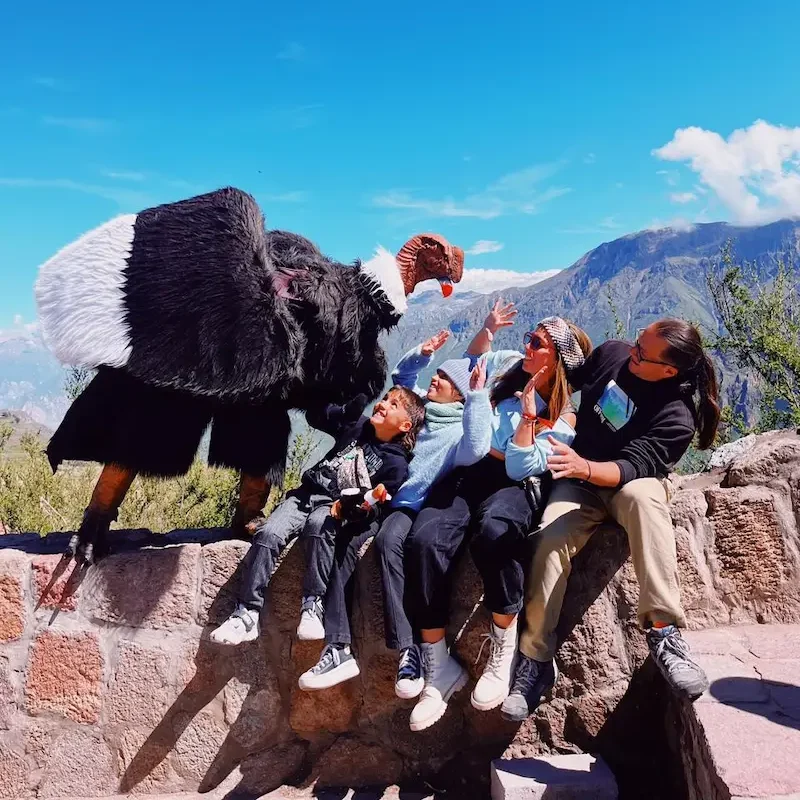 Fun tourist experience in the Colca Canyon with a person posing as a condor over a family below