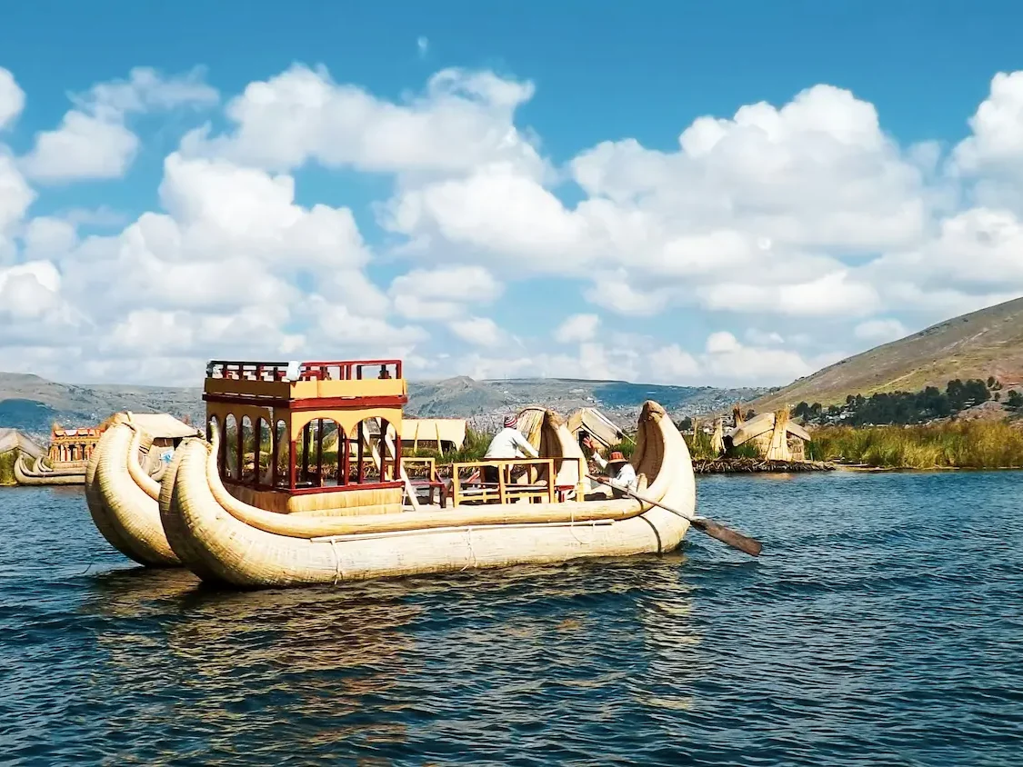 Reed boat near the Uros Floating Islands on Lake Titicaca with people onboard