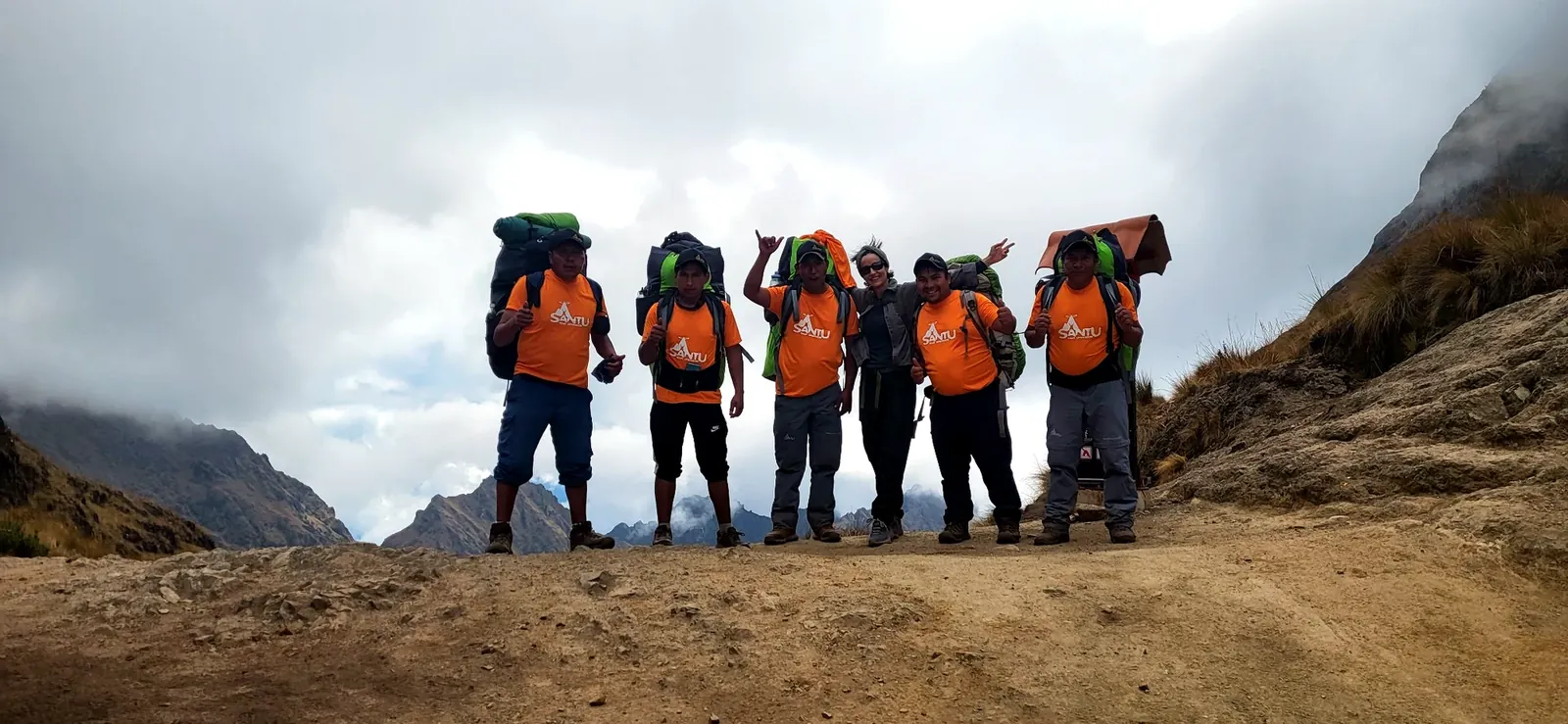 Santu trekking team with orange shirts and backpacks on an Andean trail near Cusco